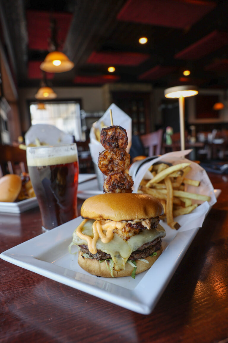 Signature burger with fries, an onion ring skewer and a draft beer