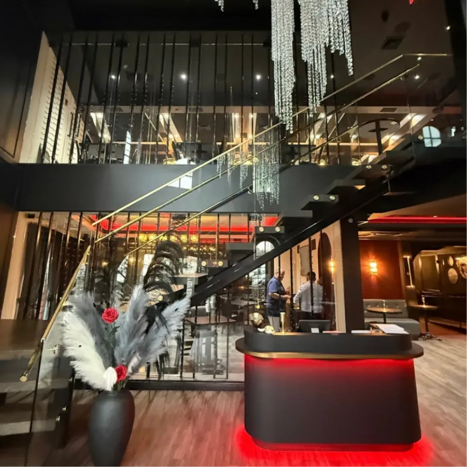 Two-story entrance at Sinner's Seafood & Steakhouse in Kenilworth, NJ, with a glass staircase, crystal chandelier and host stand