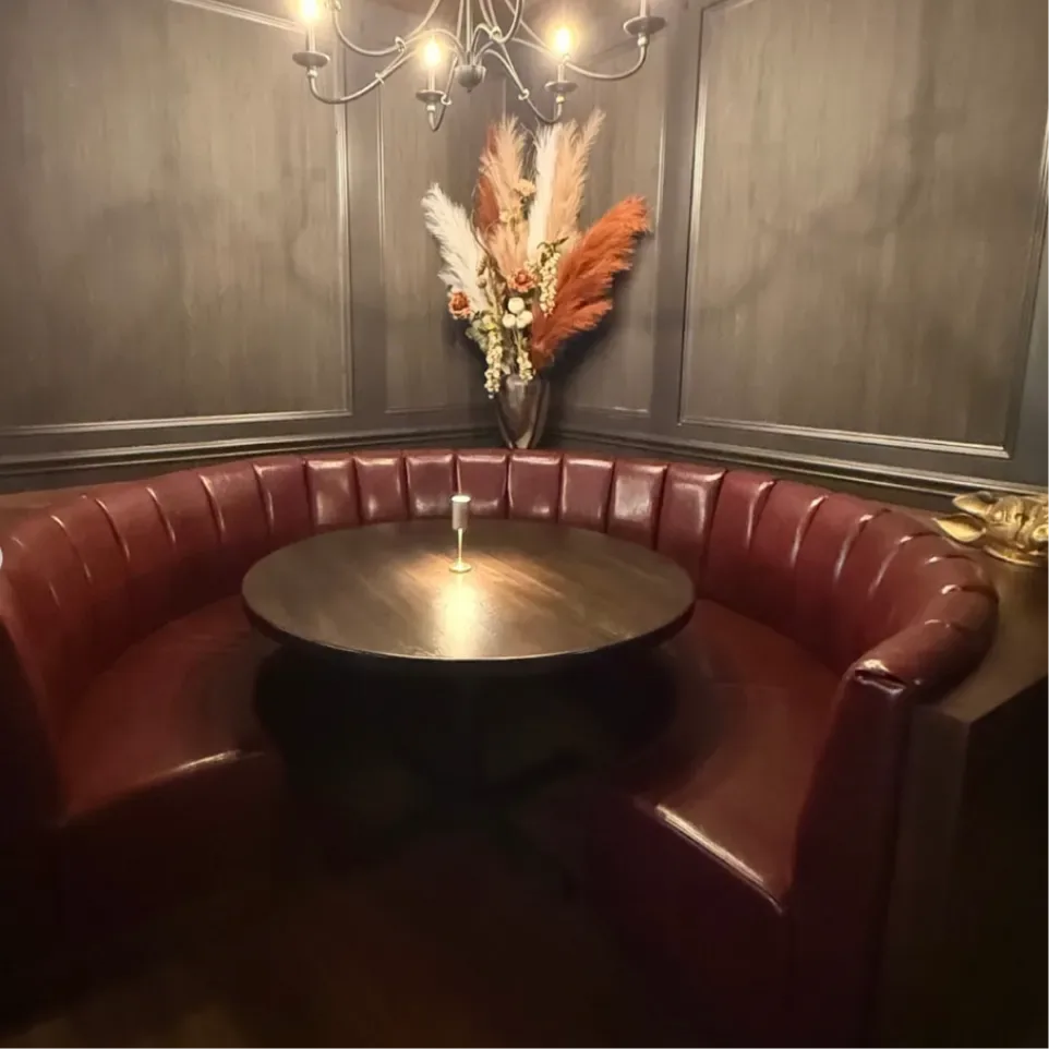 Curved red leather booth under a chandelier at Sinner's Kenilworth