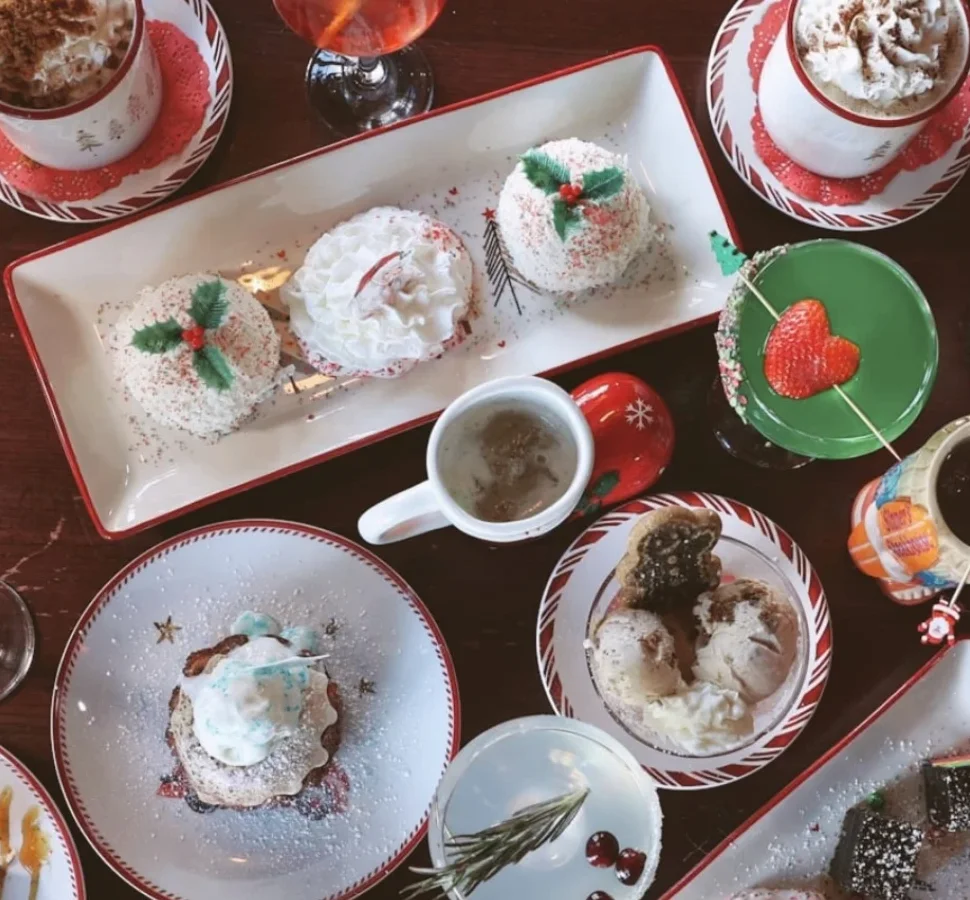 Holiday desserts and hot cocoa on Christmas plates, seen from above
