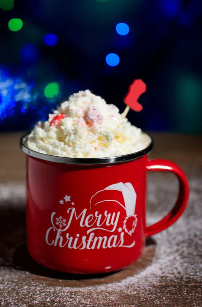 Hot cocoa with whipped cream and peppermint in a red Merry Christmas mug