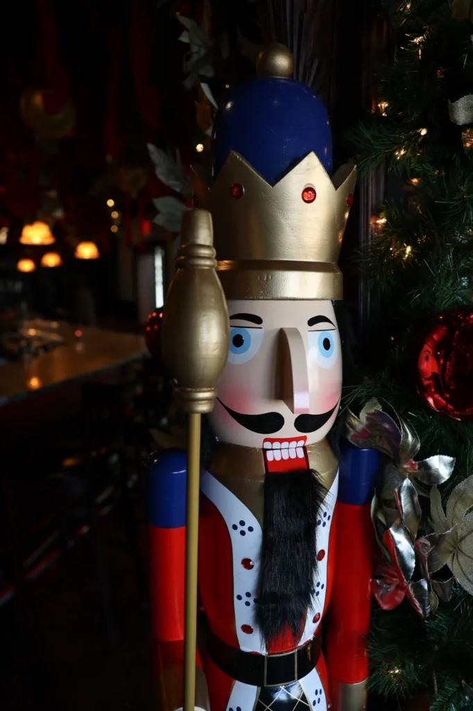 Life-size nutcracker beside a decorated Christmas tree