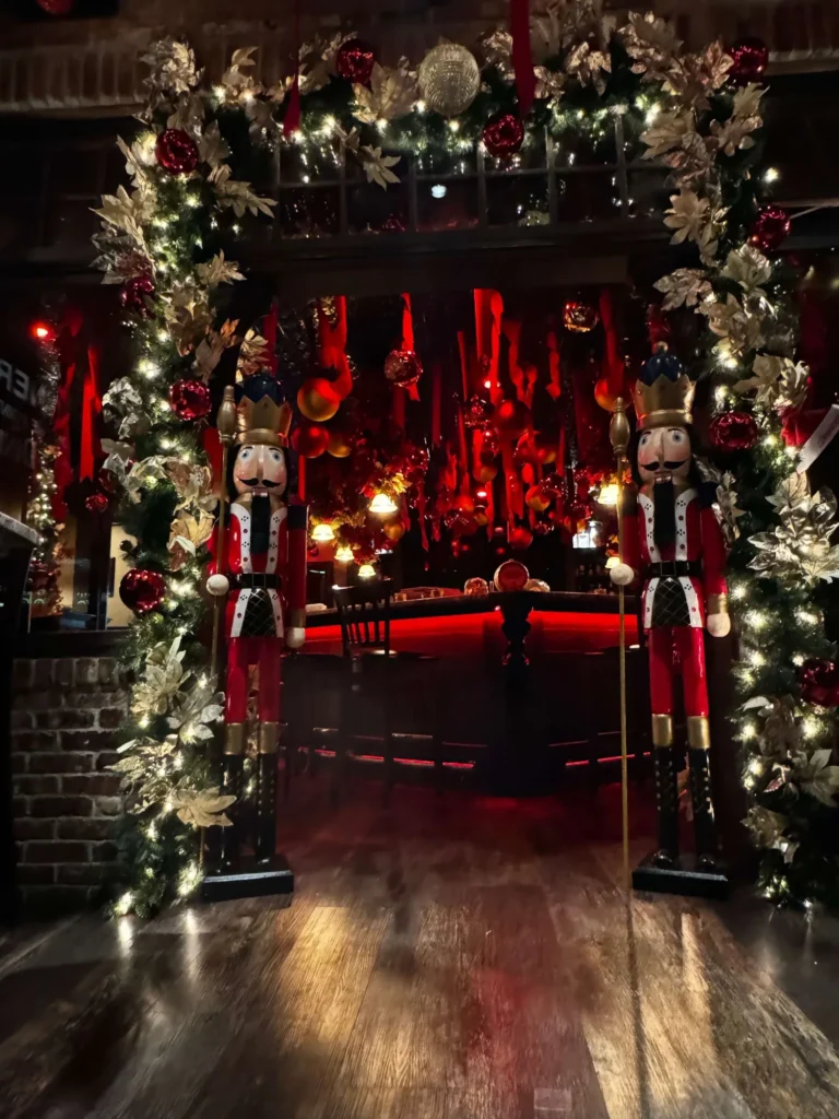 Two life-size nutcrackers guard a garland arch lit with Christmas lights at Sinner's Seafood & Steakhouse