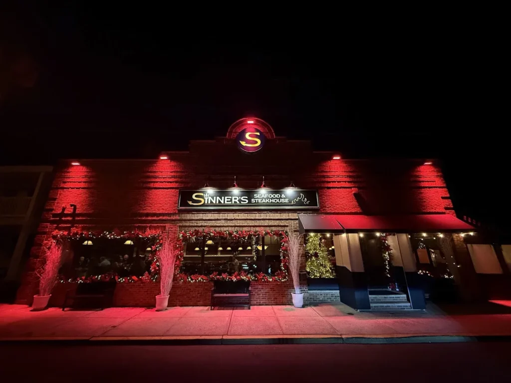 Sinner's Seafood & Steakhouse in Point Pleasant Beach at night, lit red with garlands in every window